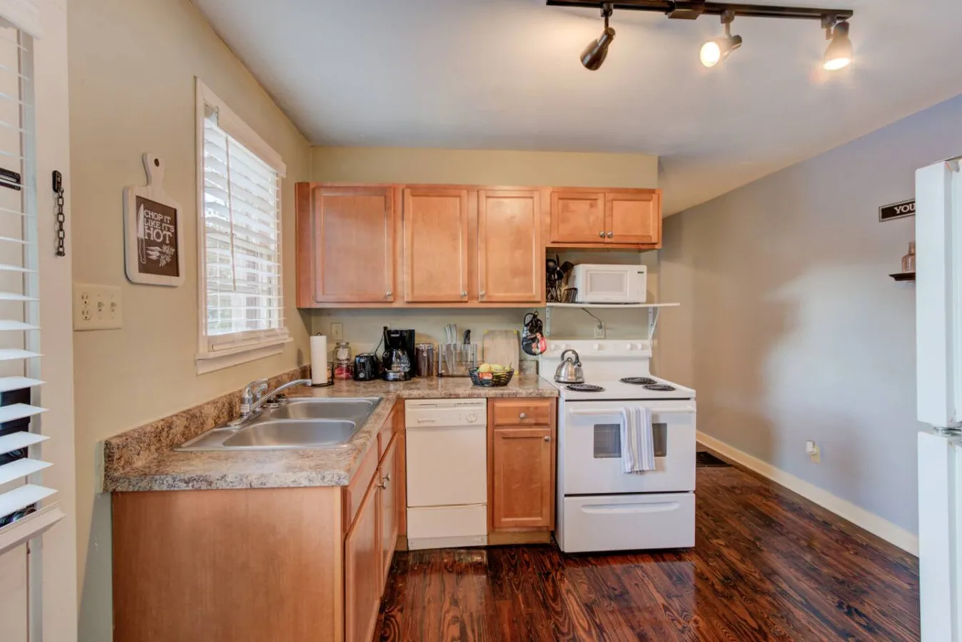 A compact kitchen with wooden cabinets, a countertop, and an electric range.