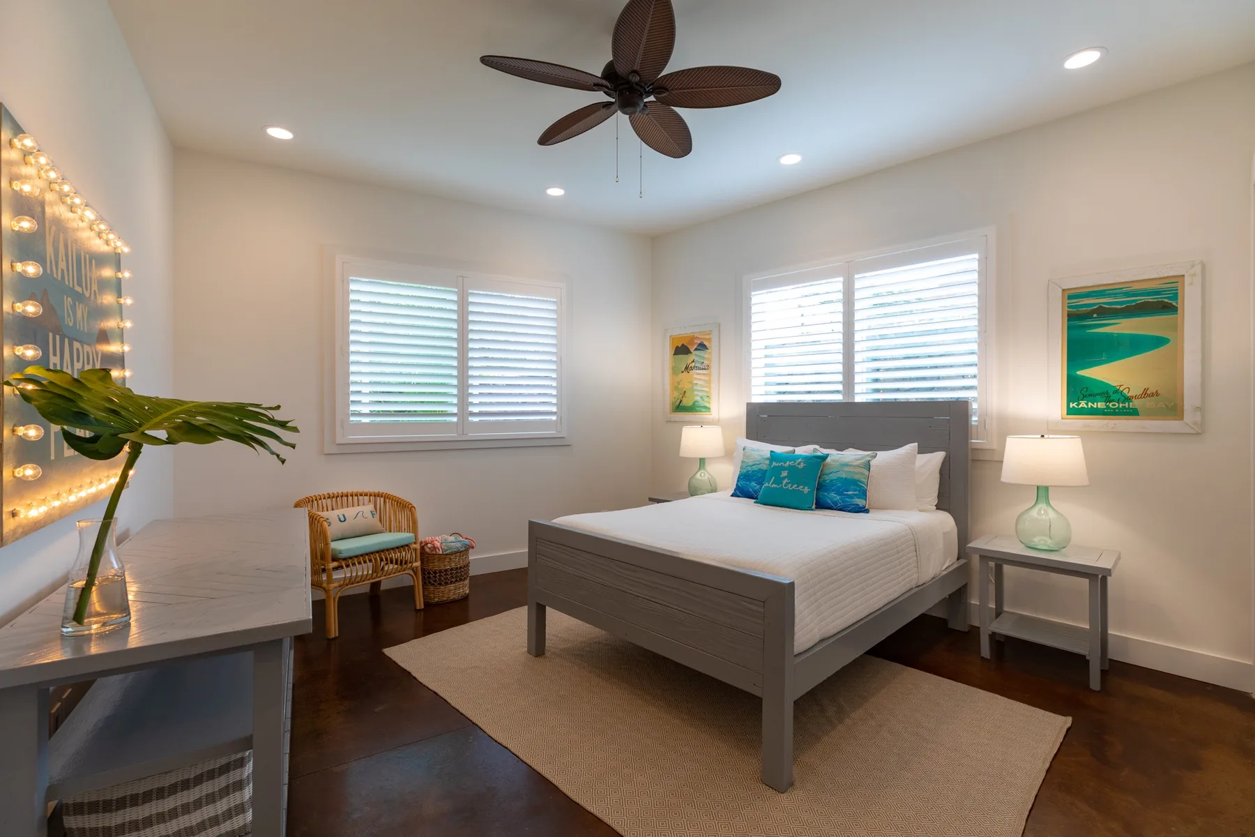 A bedroom with a large bed, bedside tables, and windows with blinds.