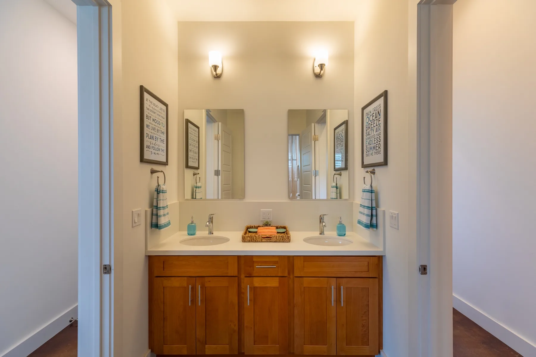 A bathroom vanity with two sinks sits beneath a wide mirror.