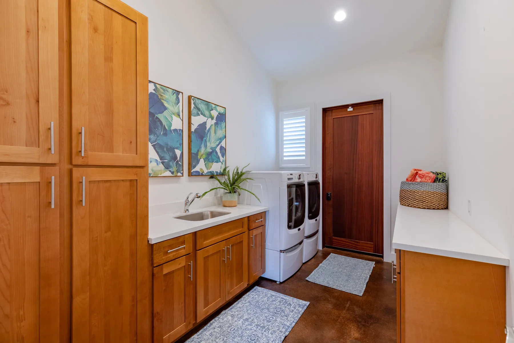A bright laundry room with wooden cabinets, a counter, and laundry machines.