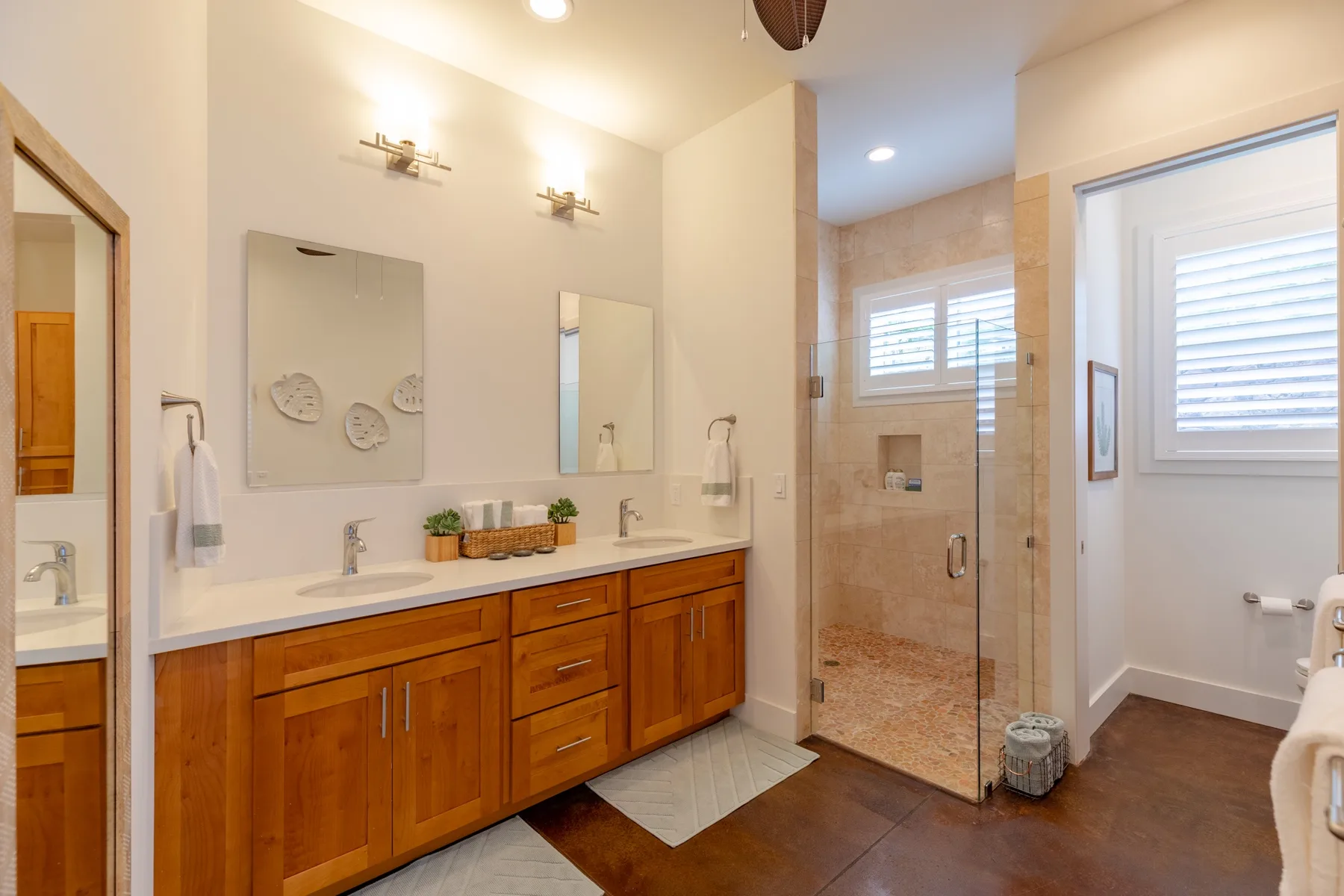 A bright bathroom with a long vanity and a glass-enclosed shower.