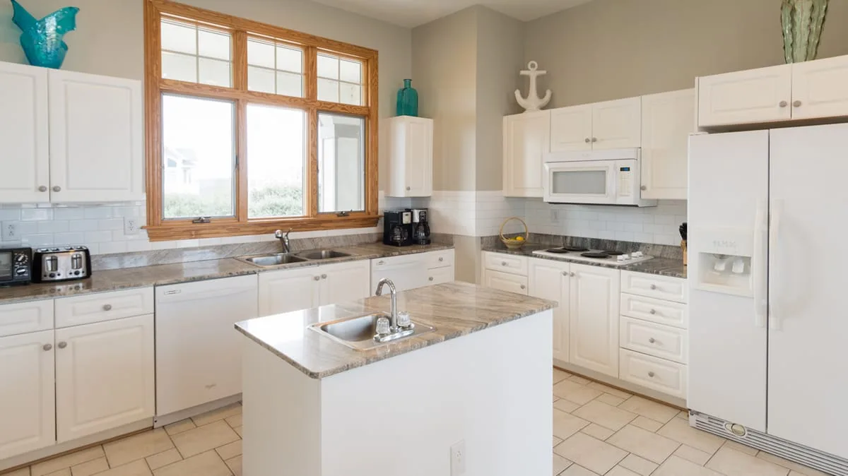 Una cocina luminosa con gabinetes blancos y una isla central.
