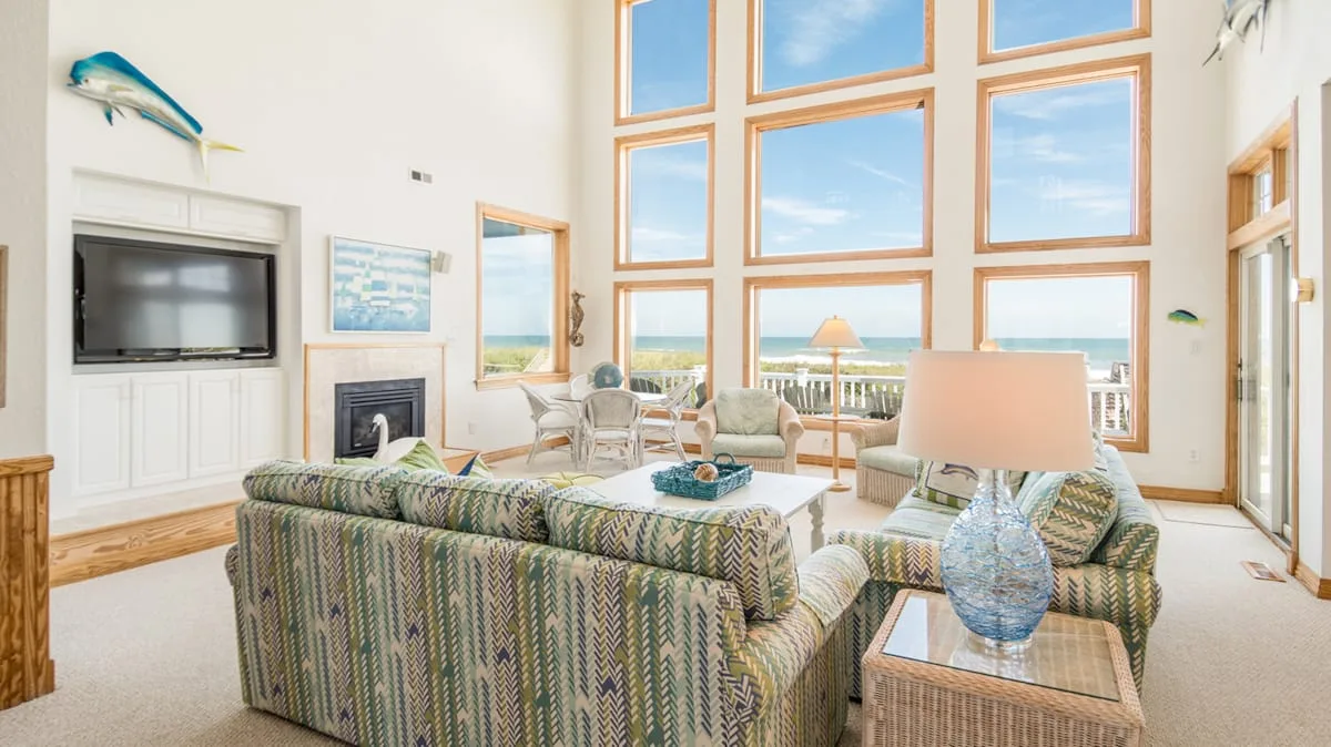 Una sala luminosa con asientos estampados y grandes ventanas con vista al océano.
