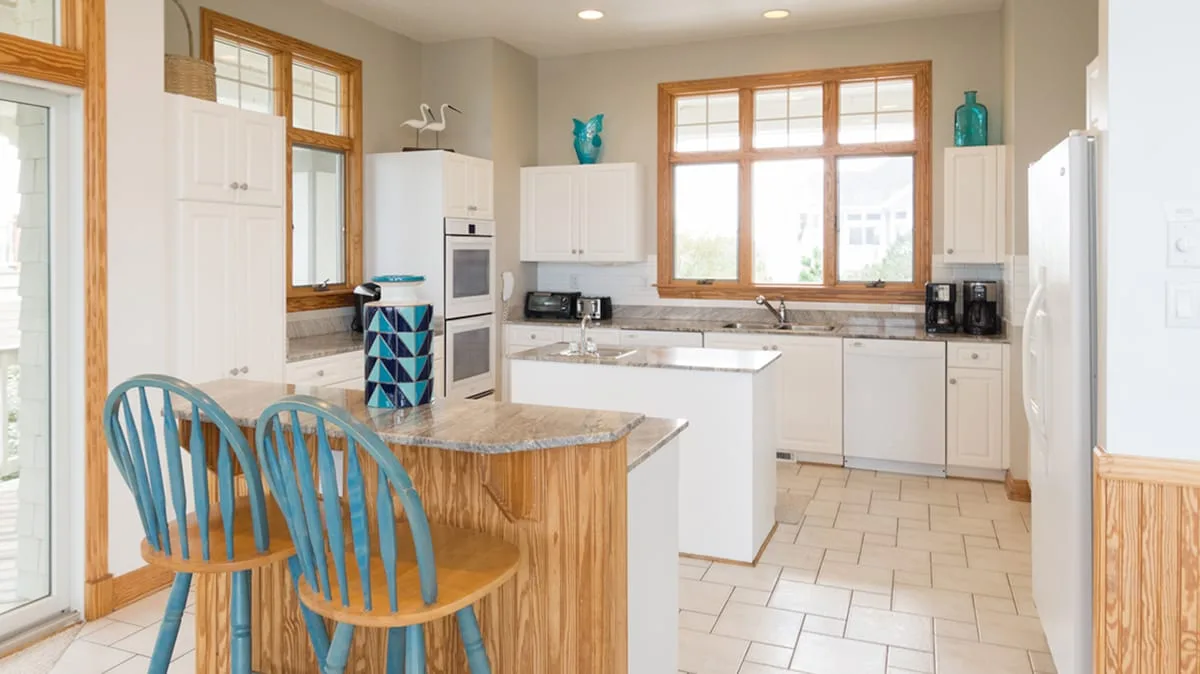 Una cocina luminosa con una isla de frente de madera y asientos azules.