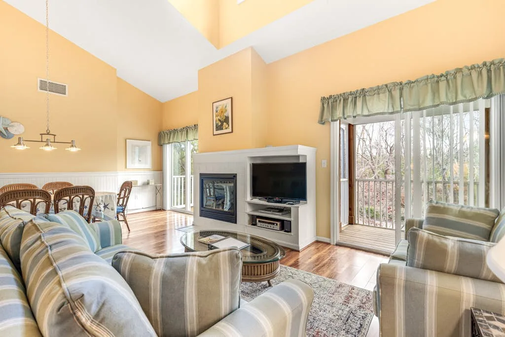 A bright living room with seating around a fireplace and television.