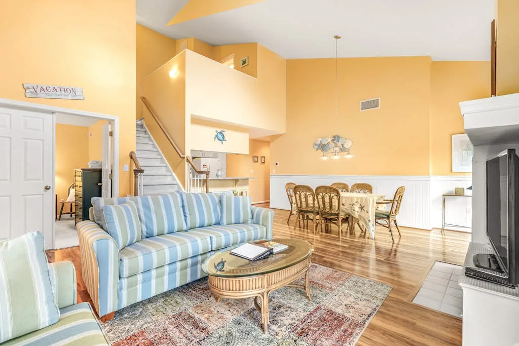A bright living and dining area with striped seating and a dining table.