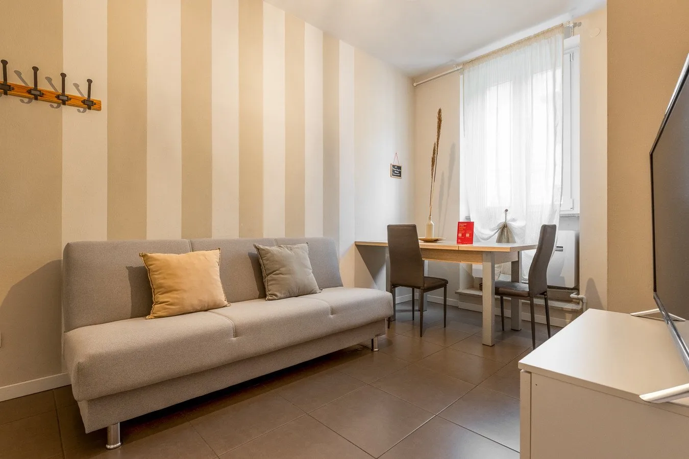Una sala de estar y comedor con sofá, mesa y una ventana grande.