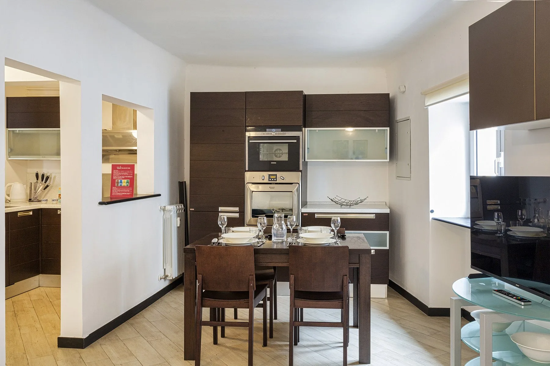 A dining area with a set table stands in front of dark kitchen cabinets.