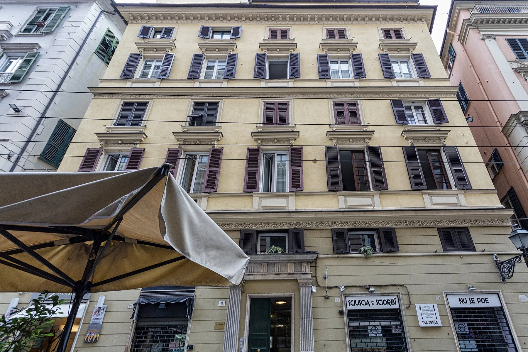 A multi-story building facade with rows of windows and a café awning.