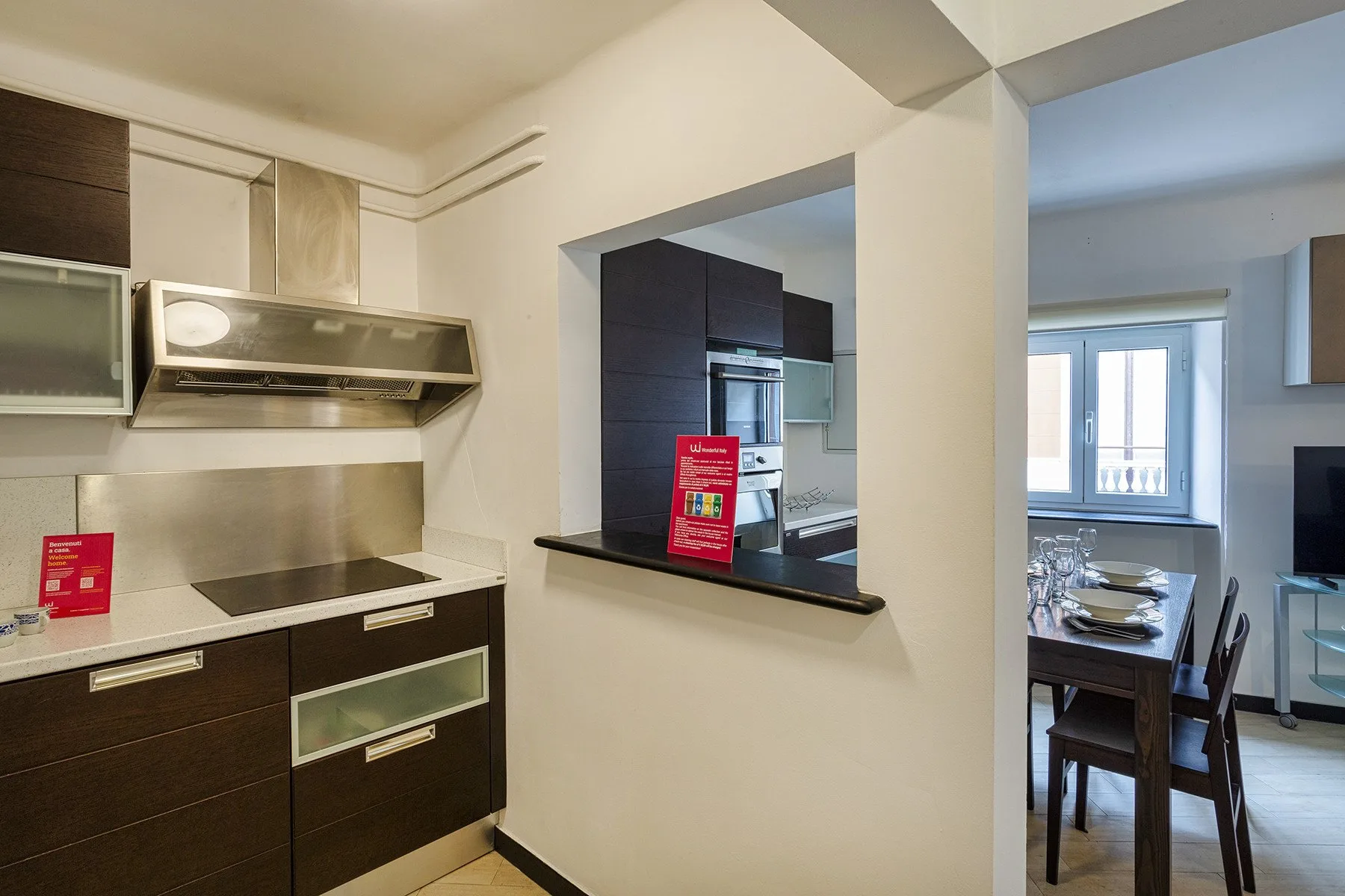 A kitchen with dark cabinets and a pass-through opening to a dining area.