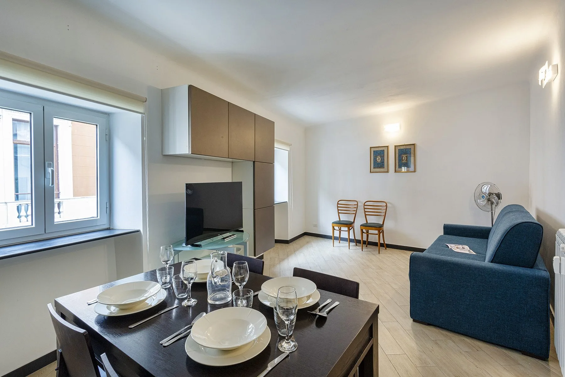 A bright living and dining area with a set table and blue seating.
