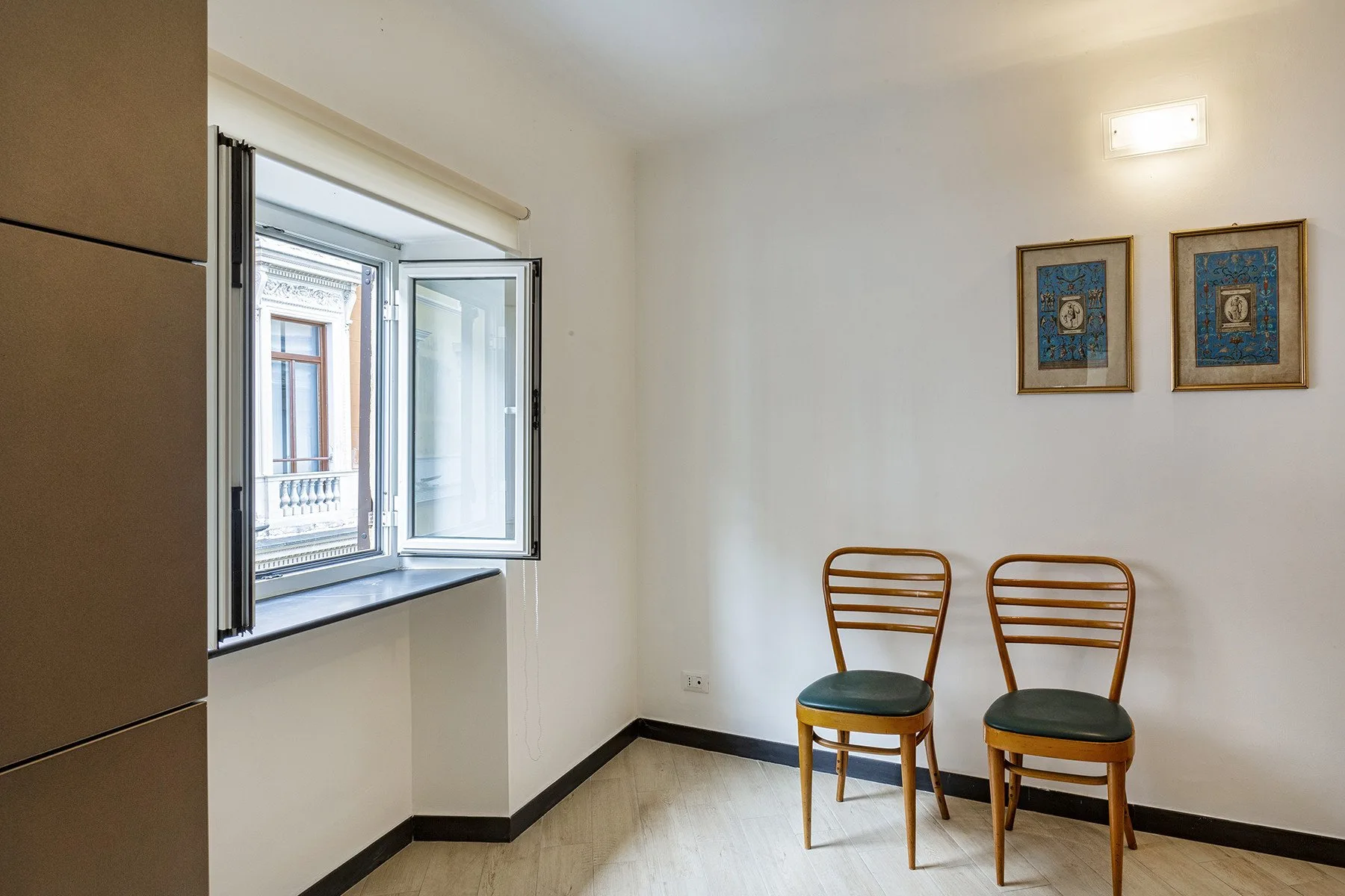 A bright room with two chairs beside an open window.