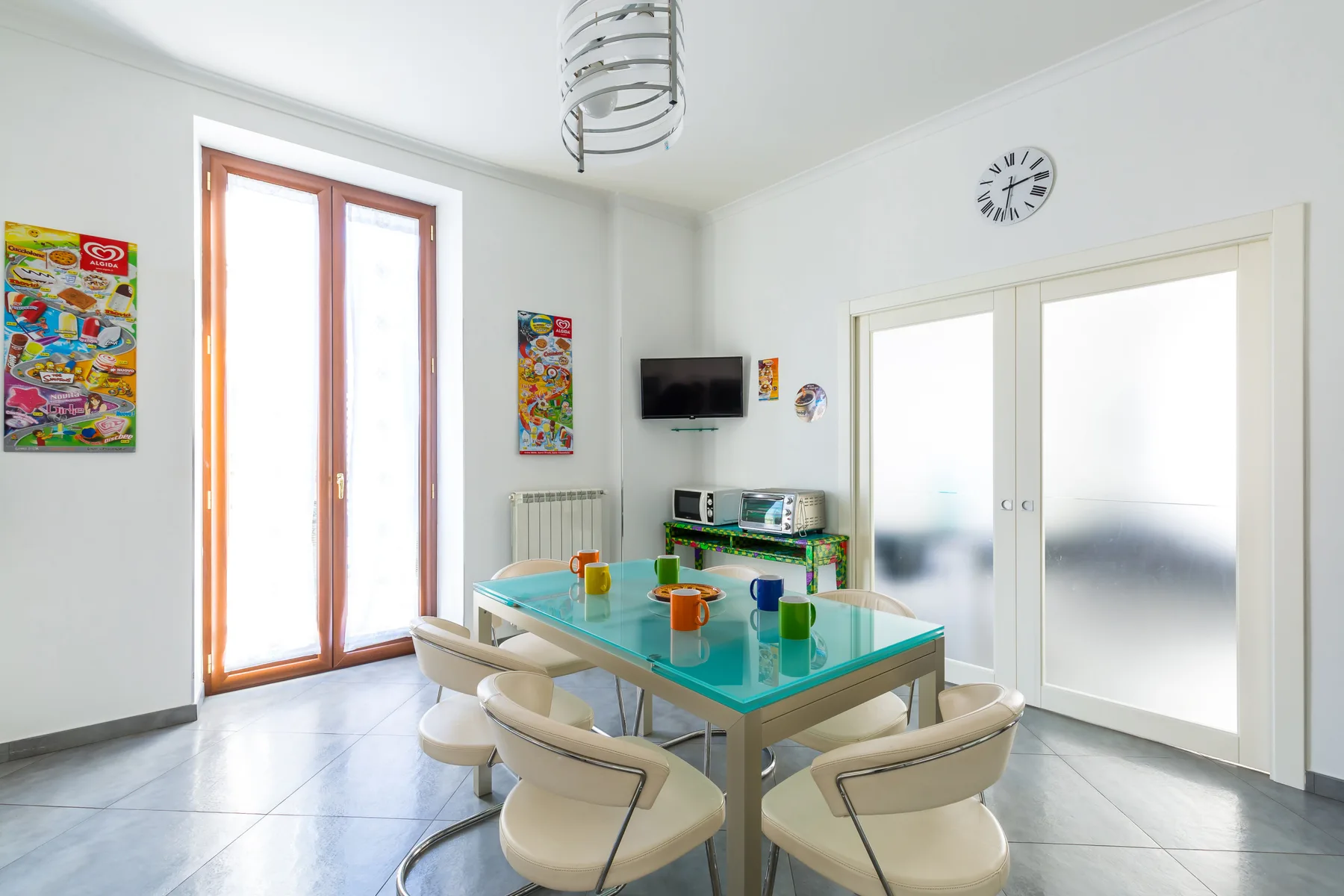 A bright dining area with a glass table, seating, and large windows.