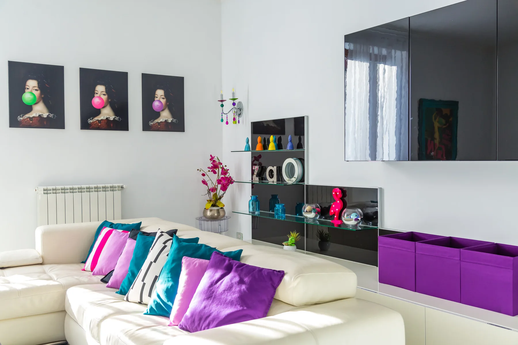 A bright living room with white seating and colorful cushions.