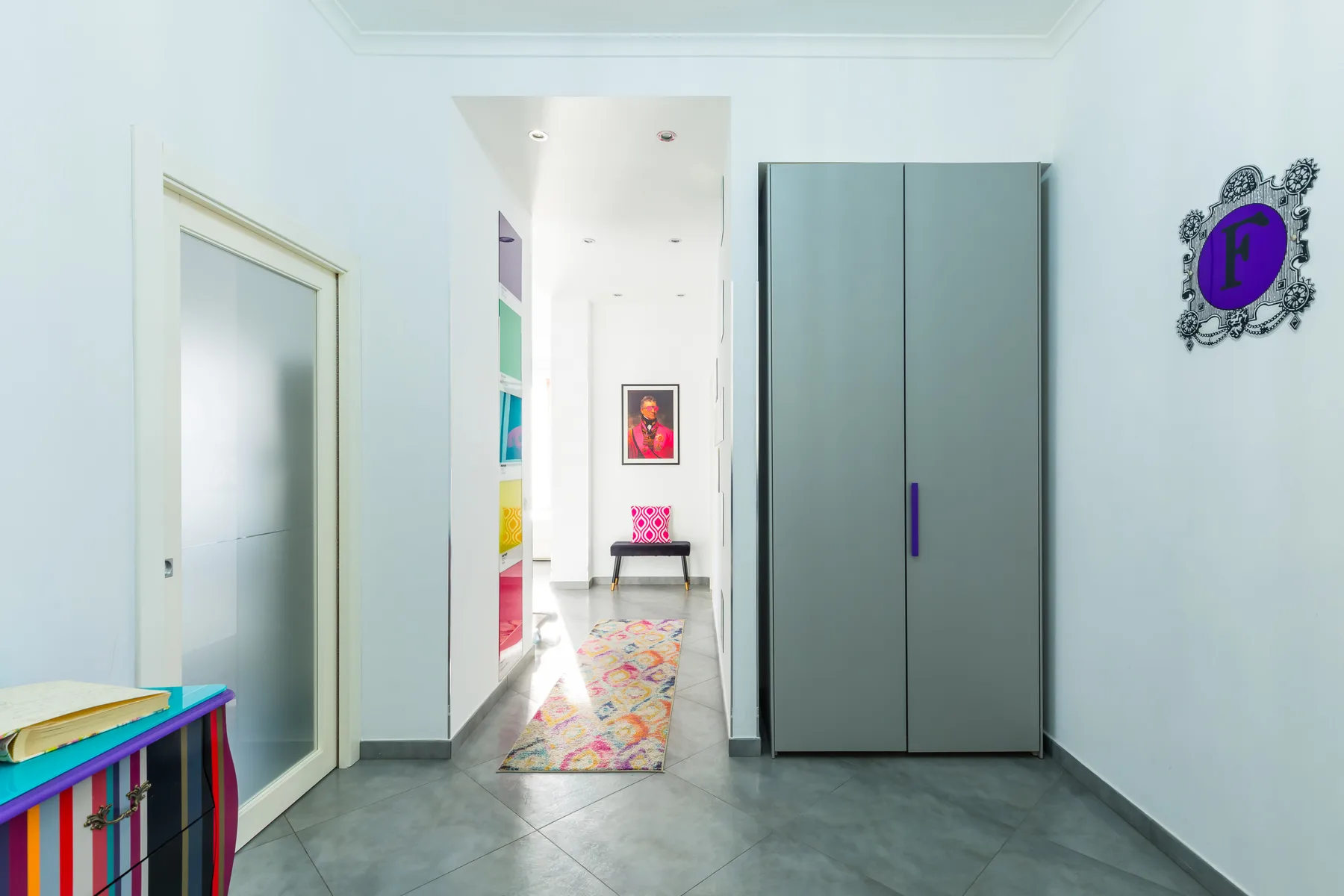 A bright hallway with a gray wardrobe and a colorful runner.