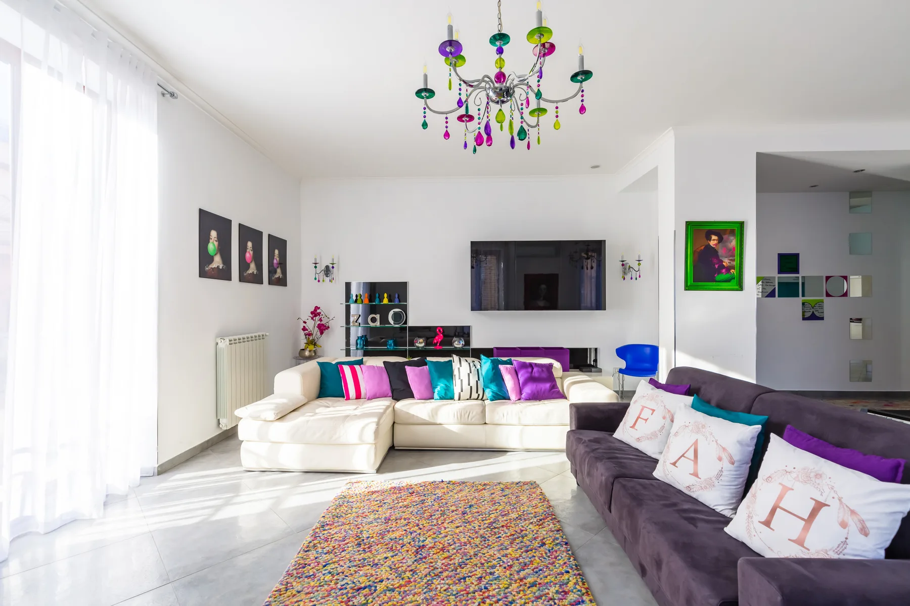 A bright living room with colorful seating and a chandelier.