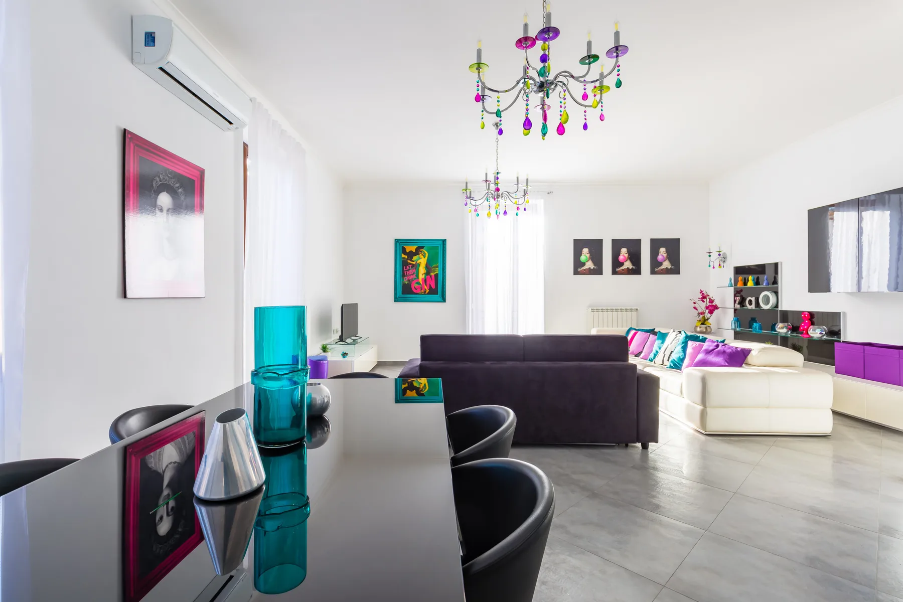 A bright living room with seating, a glossy table, and colorful ceiling lights.