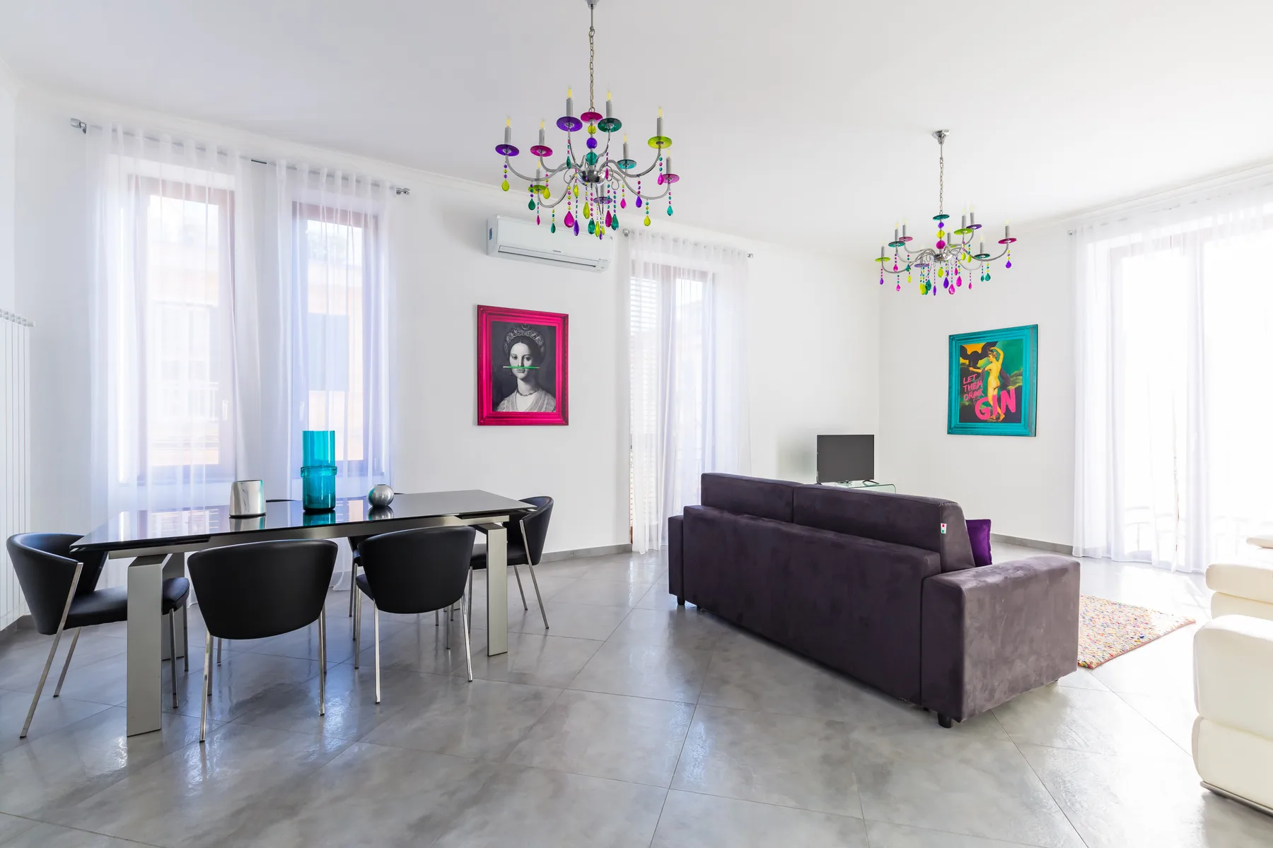 A bright living and dining room with a dark seating area and table.