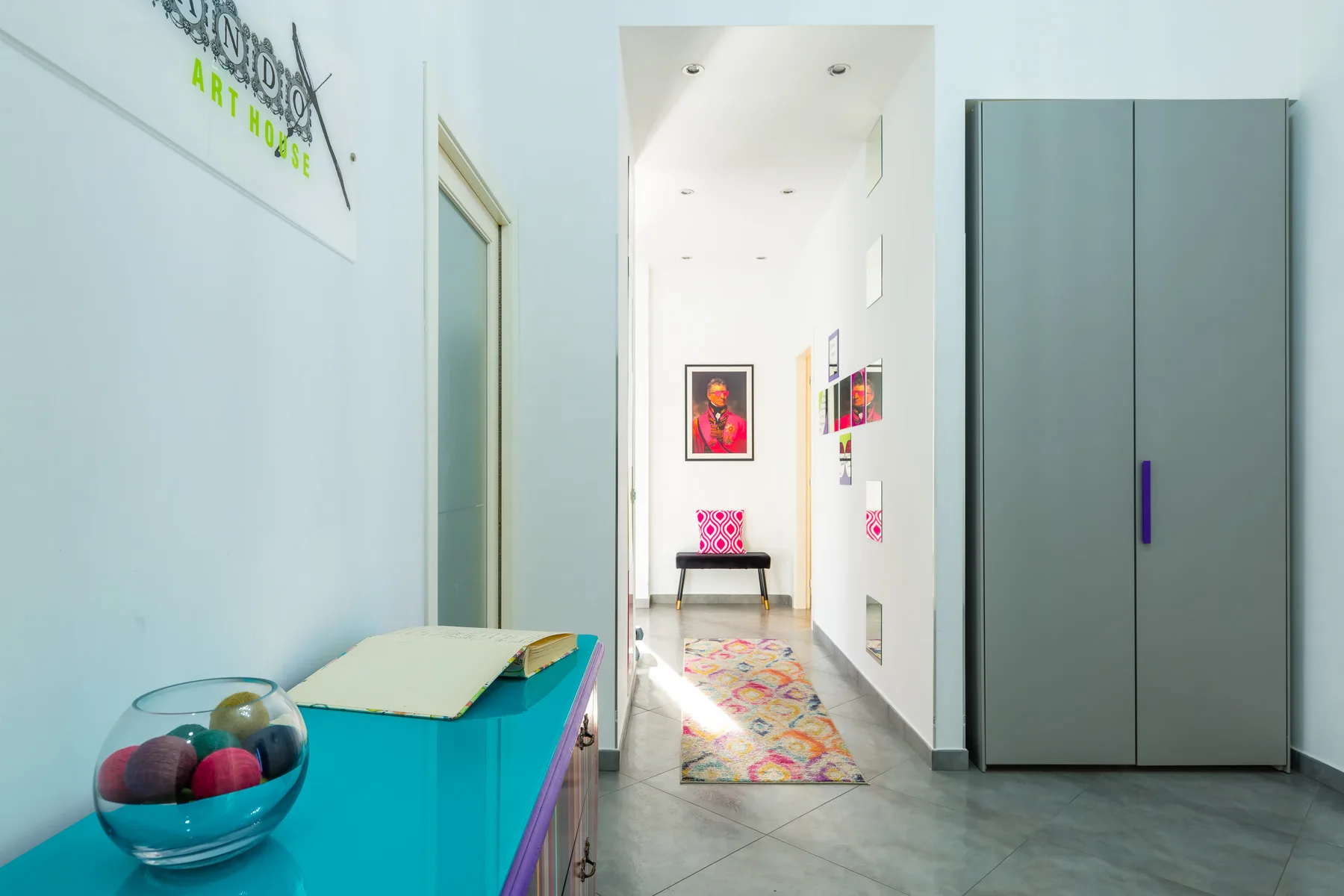 A bright hallway with colorful artwork and a tall gray cabinet.