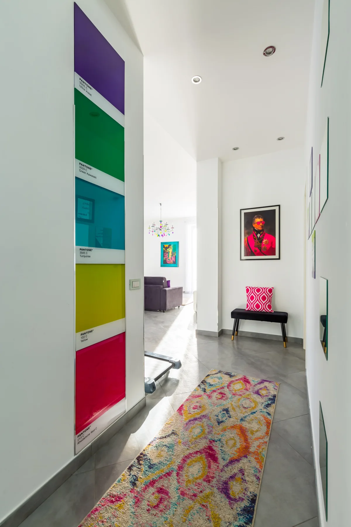 A bright hallway features a colorful runner and framed artwork.