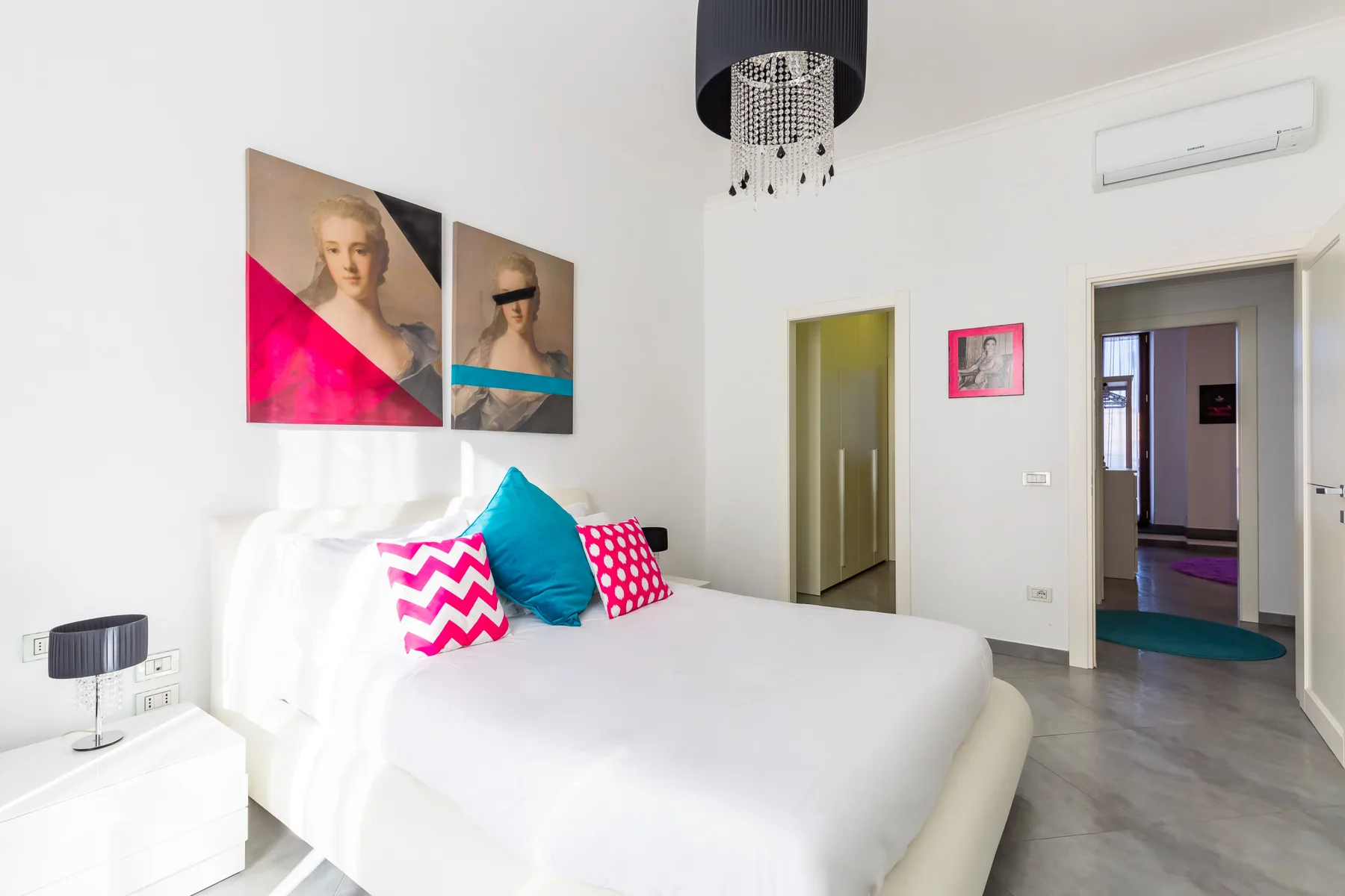 A bright bedroom with a white bed and colorful accent pillows.