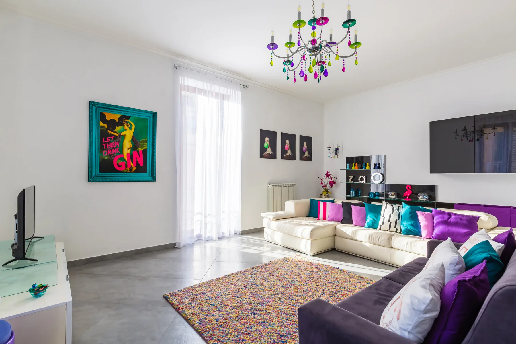 A colorful living room with sectional seating, a patterned rug, and tall windows.