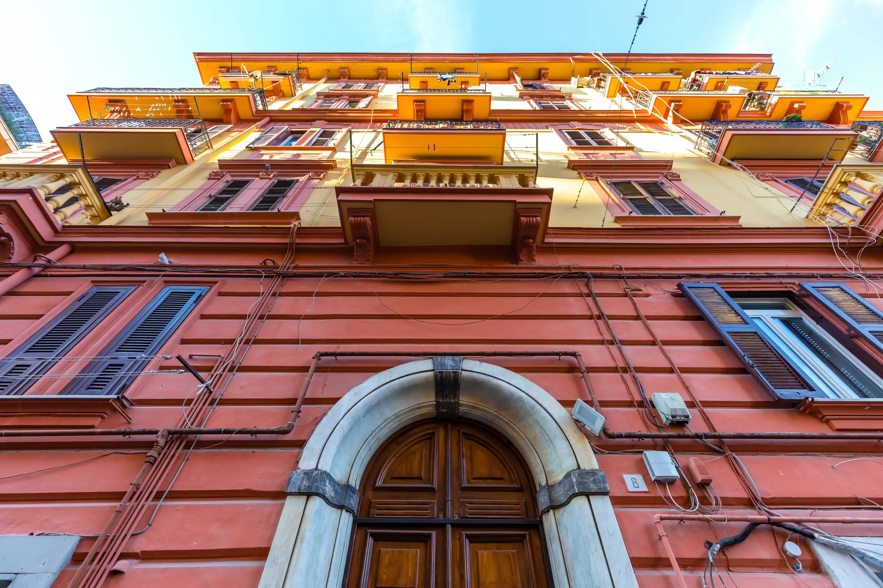 A colorful multi-story building facade with rows of windows and a large arched doorway.