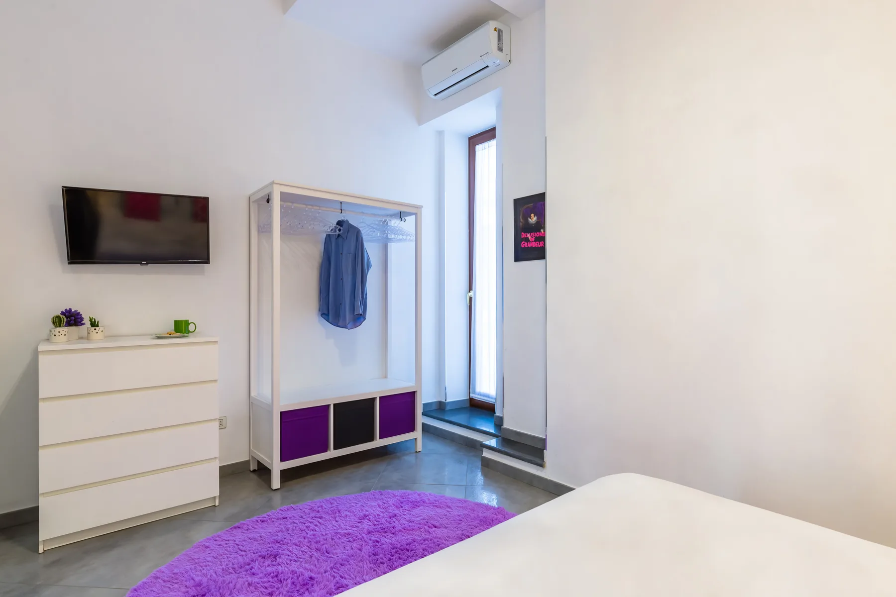 A bright bedroom with a bed, dresser, and wardrobe.
