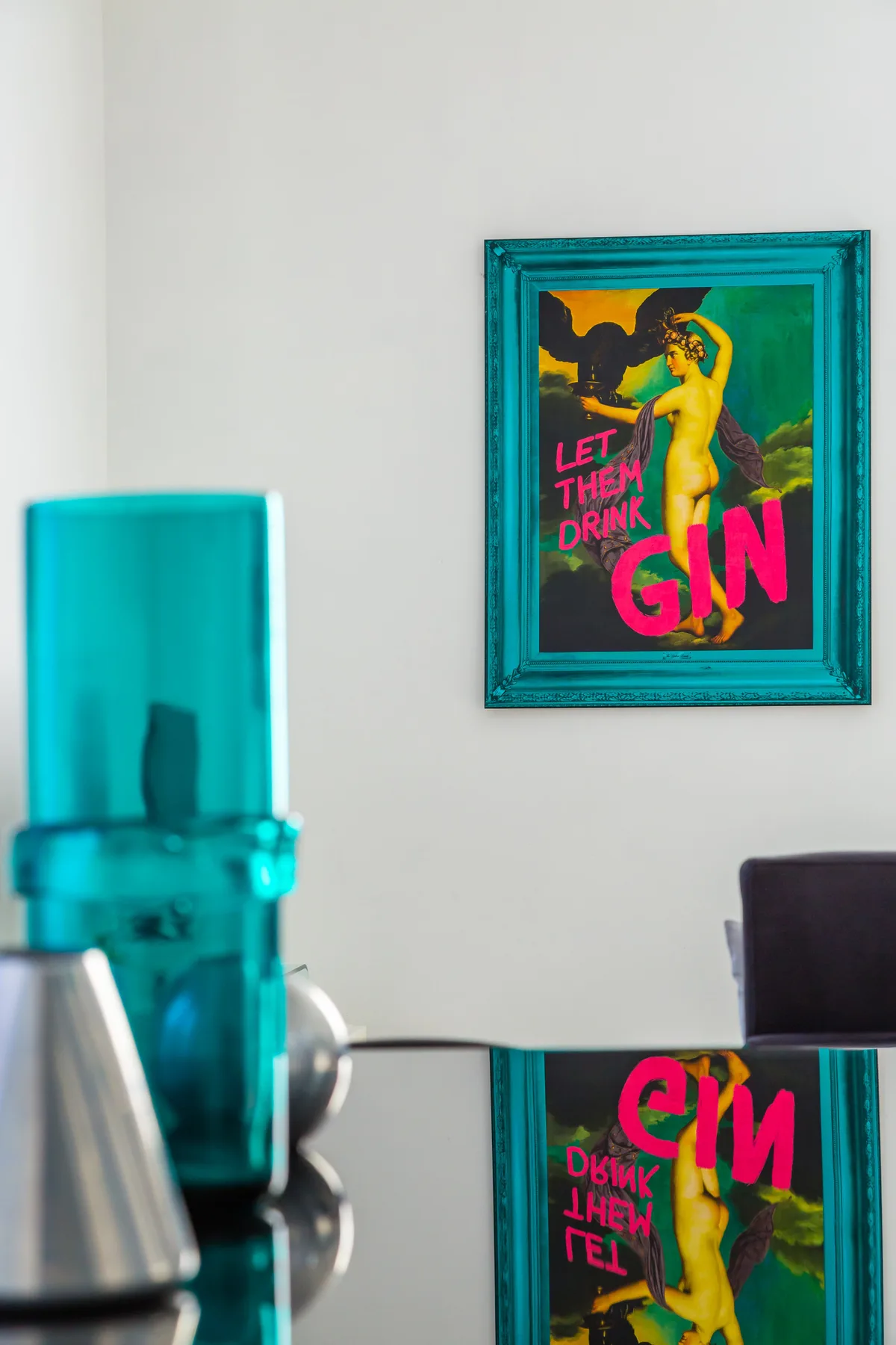 A framed colorful poster hangs above a reflective counter in a room.