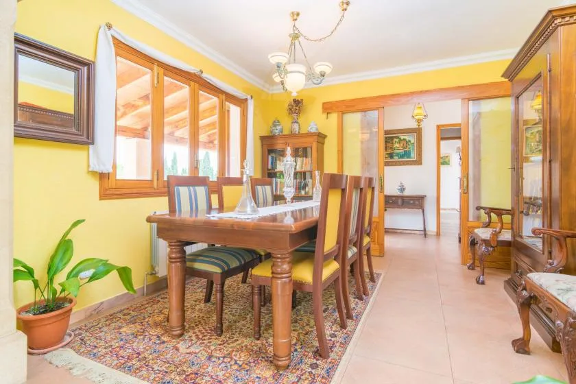 A dining room with a wooden table and chairs beside large windows.