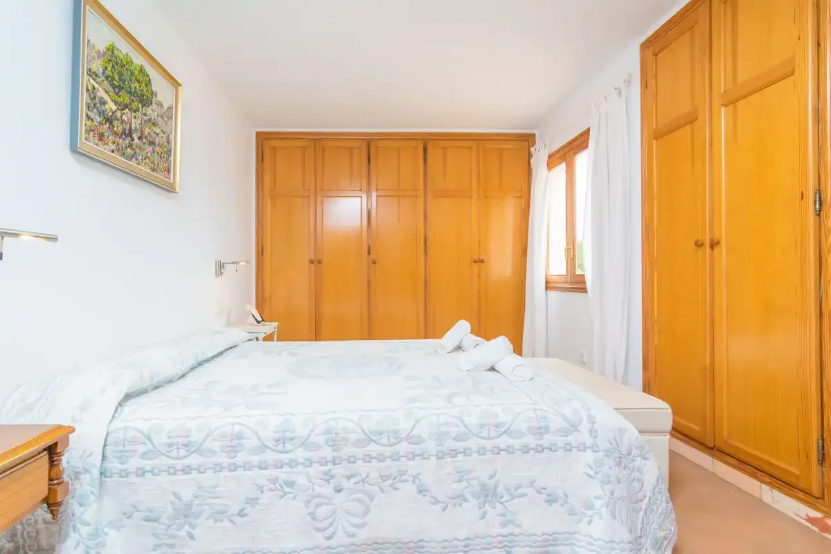 A bedroom with a bed and wooden wardrobes.