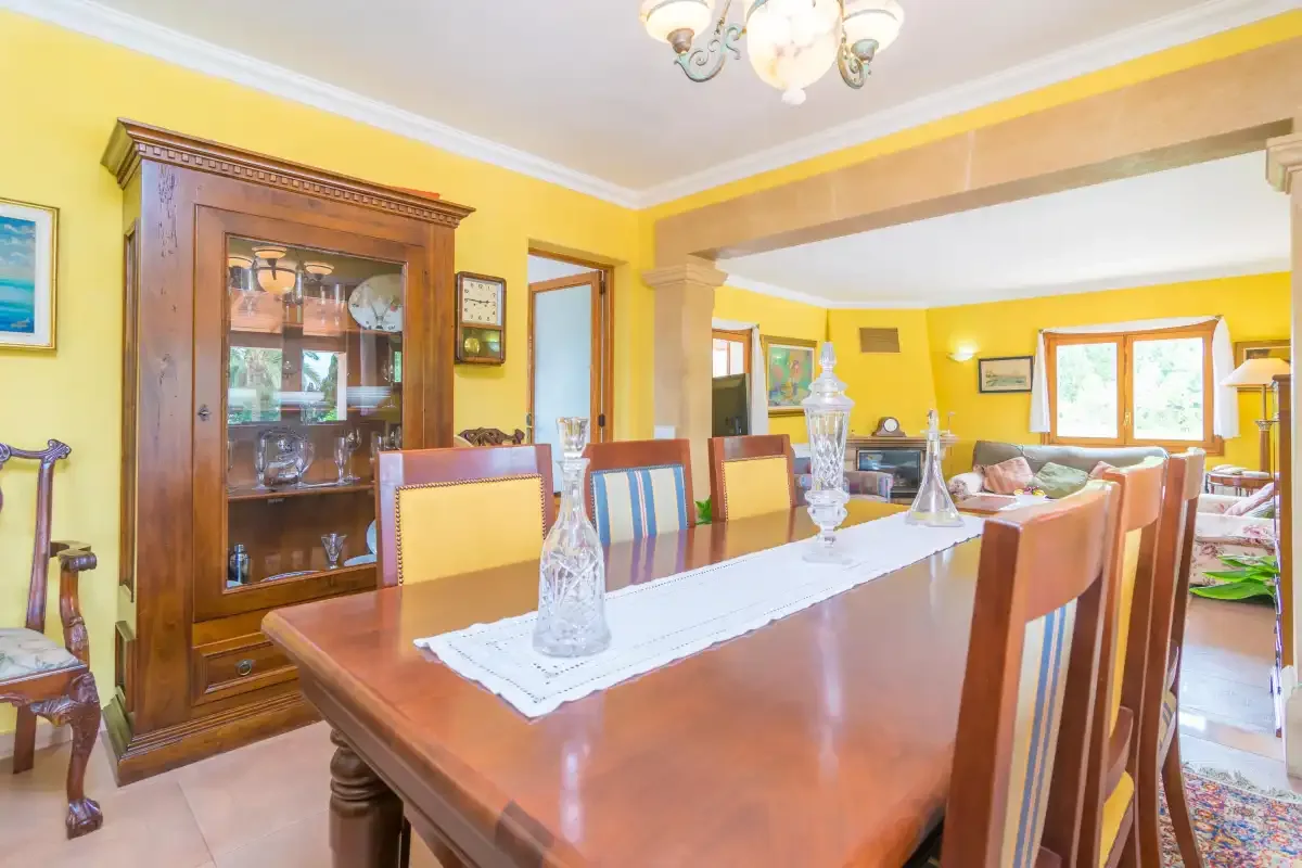 A dining room with a long wooden table and chairs beneath a chandelier.