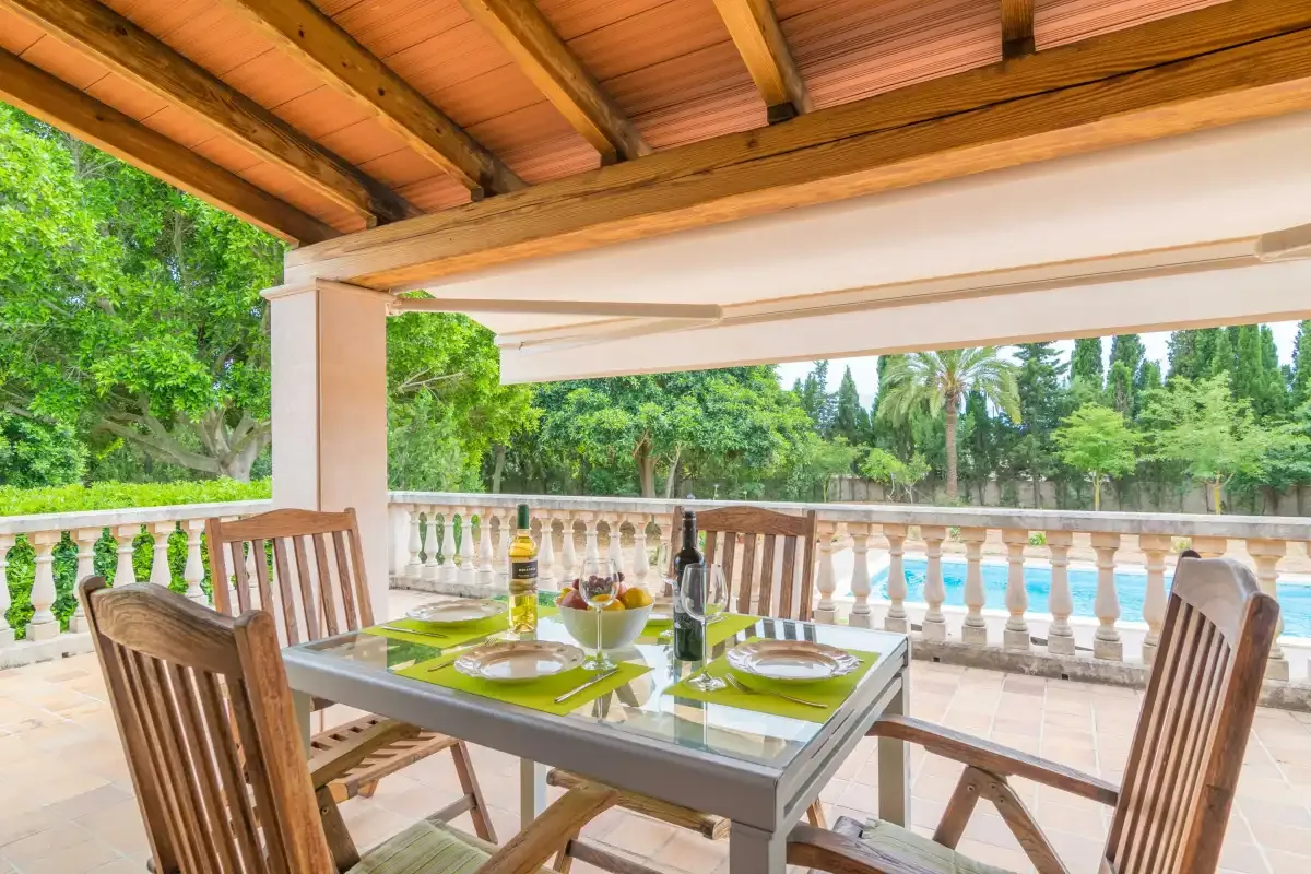 A covered outdoor dining area with a table and seating beside a balustrade.