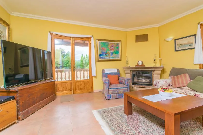 A living room with colorful seating, a television, and glass doors opening to a balcony.