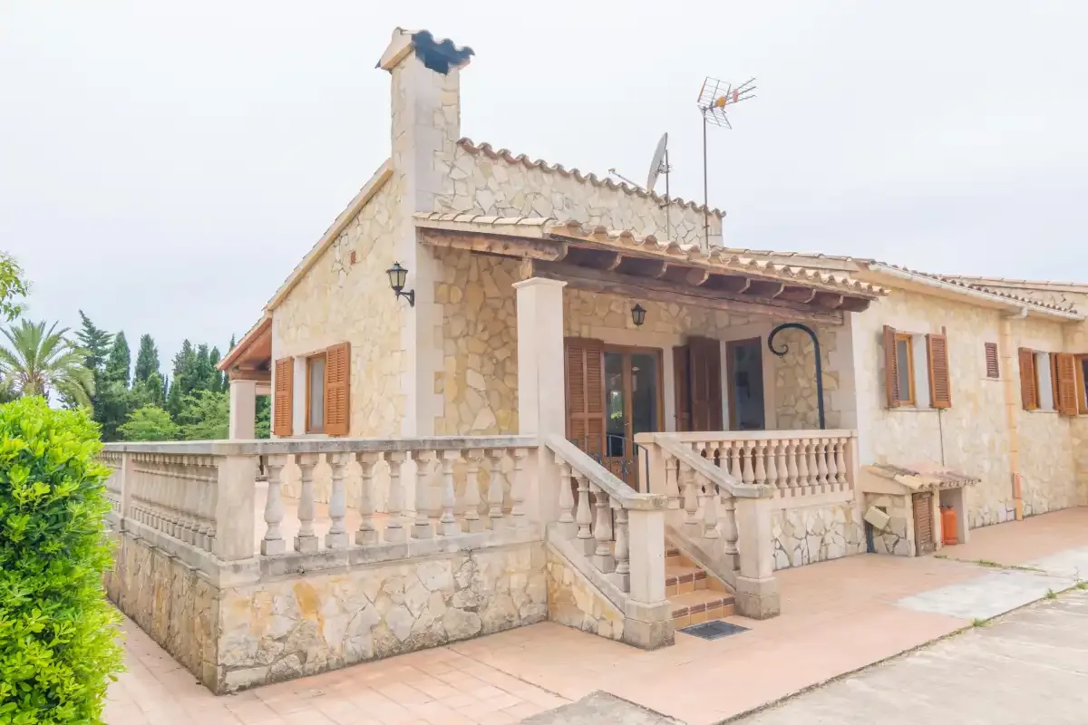 A stone house with a tiled terrace and exterior stairs.
