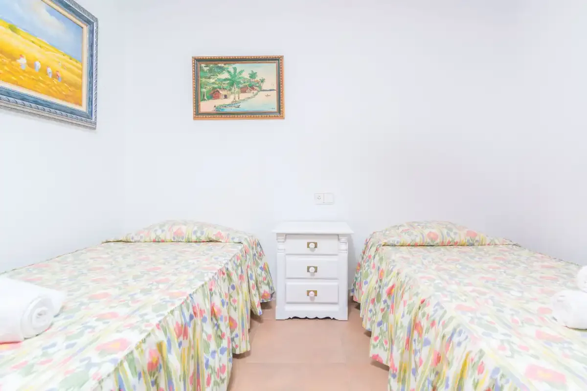 A bedroom with two beds and a small bedside table.