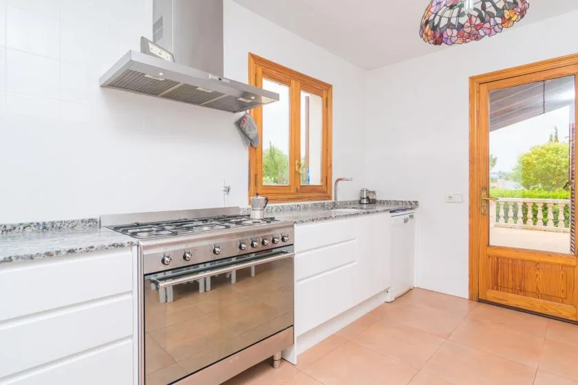 A bright kitchen with a stainless-steel range beneath a metal hood.