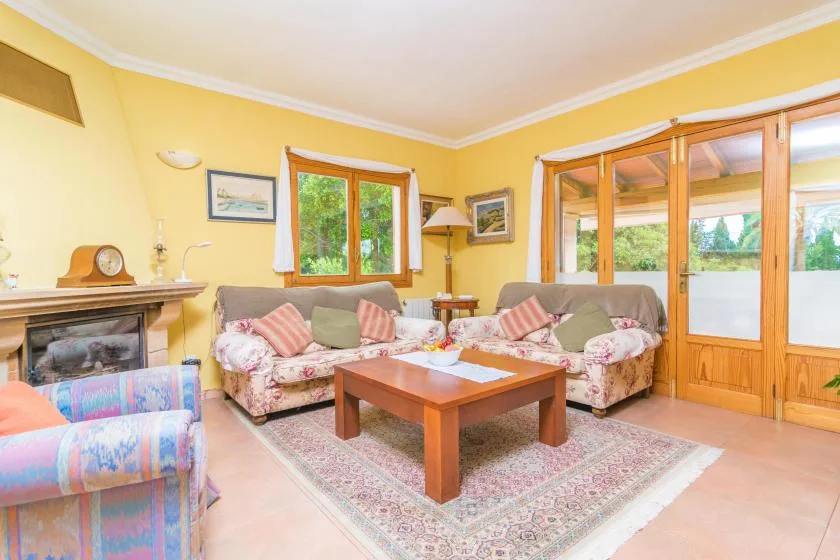 A yellow living room with patterned seating around a wooden coffee table.