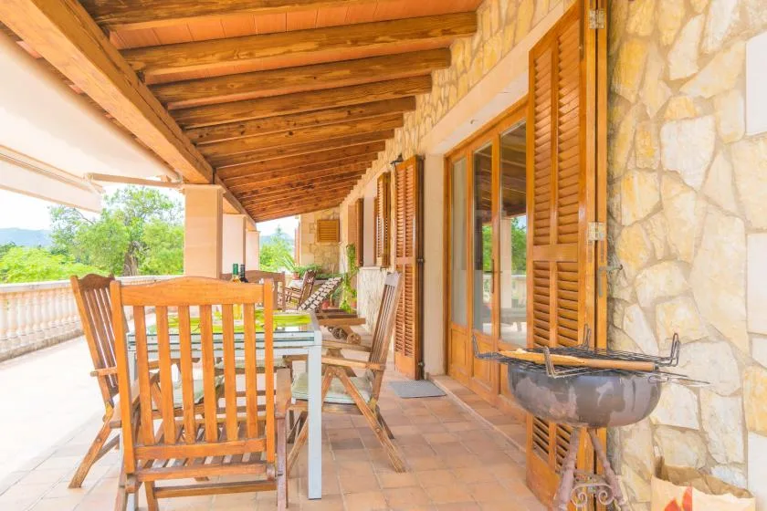 A covered patio with wooden seating and a stone wall.