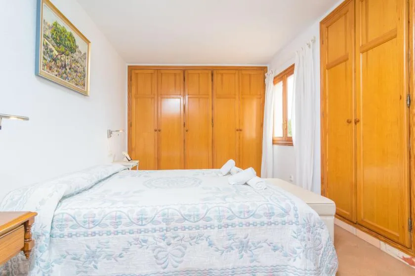 A bedroom with a bed and built-in wooden wardrobes.