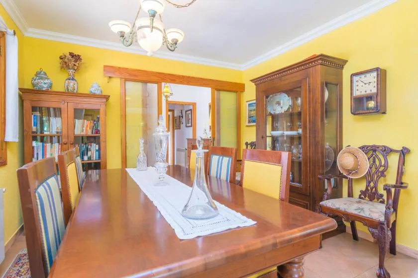 A dining room with a long wooden table and glass display cabinets.