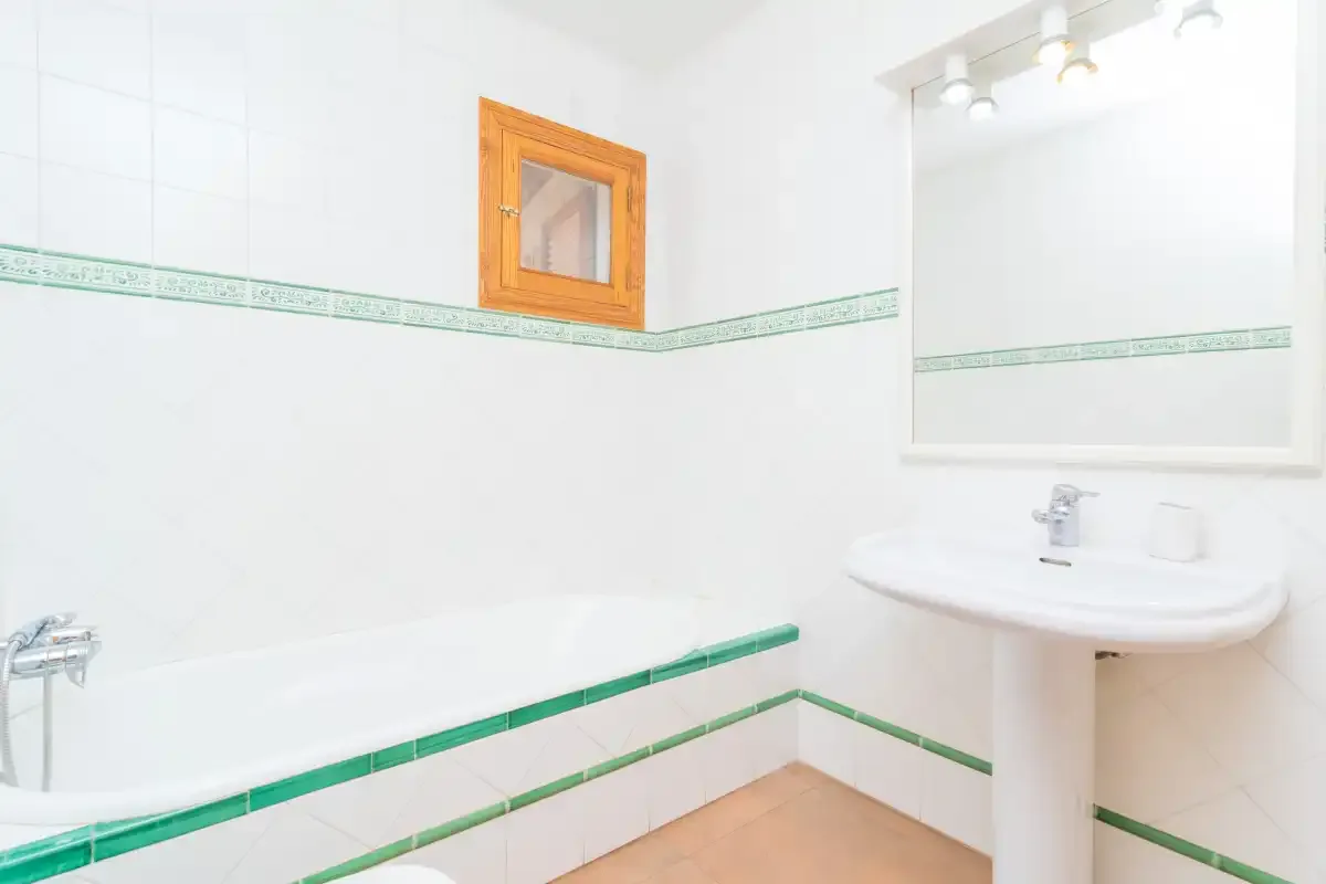 A tiled bathroom with a bathtub and a pedestal sink.