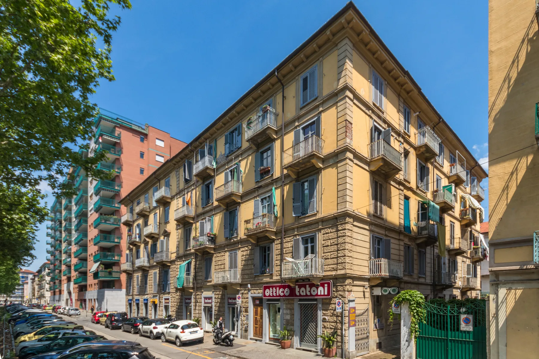 Un edificio de apartamentos de varias plantas con balcones está en una calle soleada.
