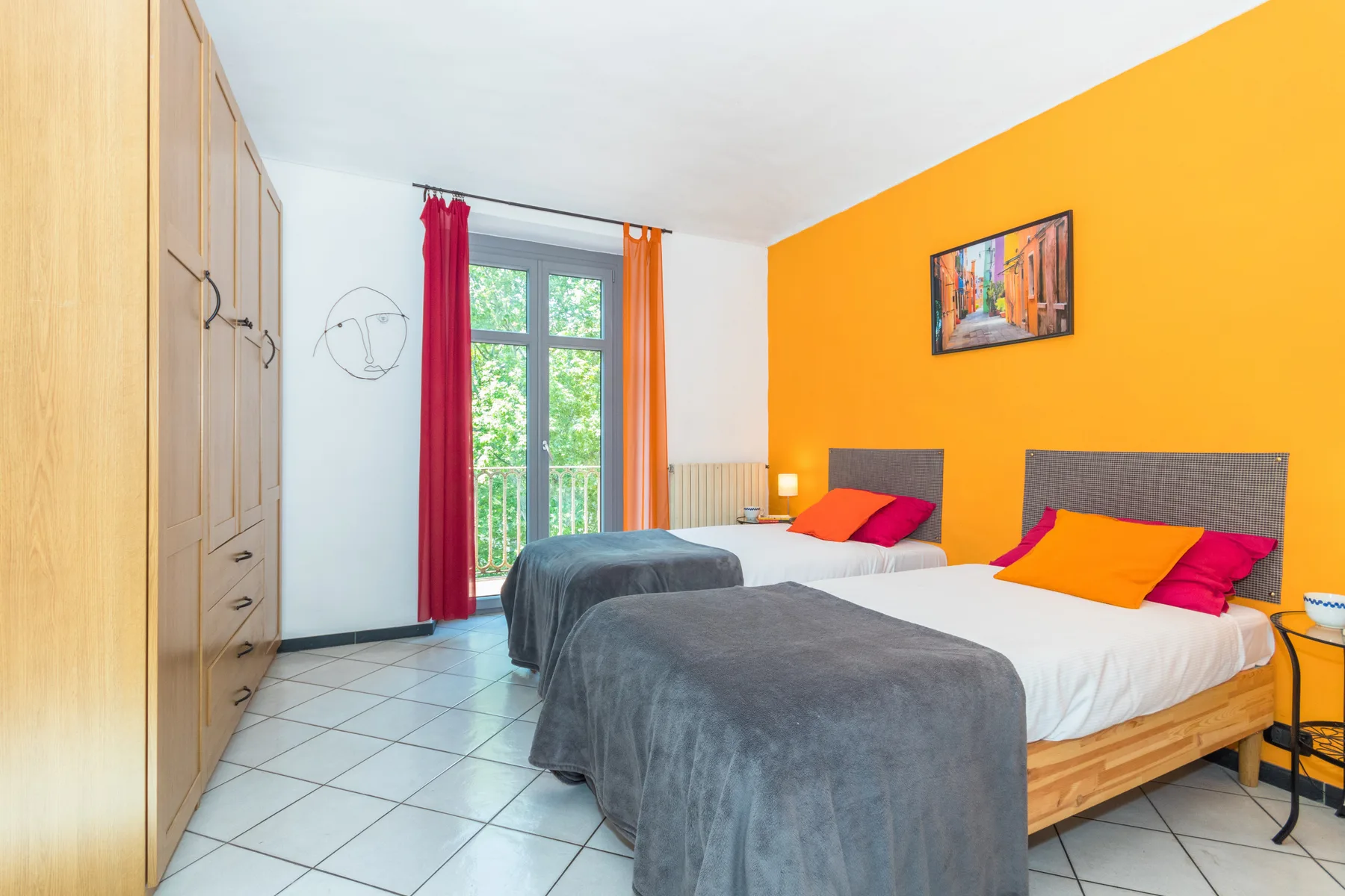 Un dormitorio con dos camas, ropa de cama gris y una pared naranja.