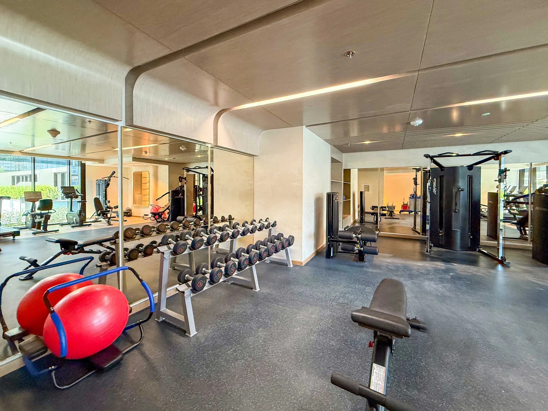 Un gimnasio con paredes espejadas, pesas y equipo de ejercicio.