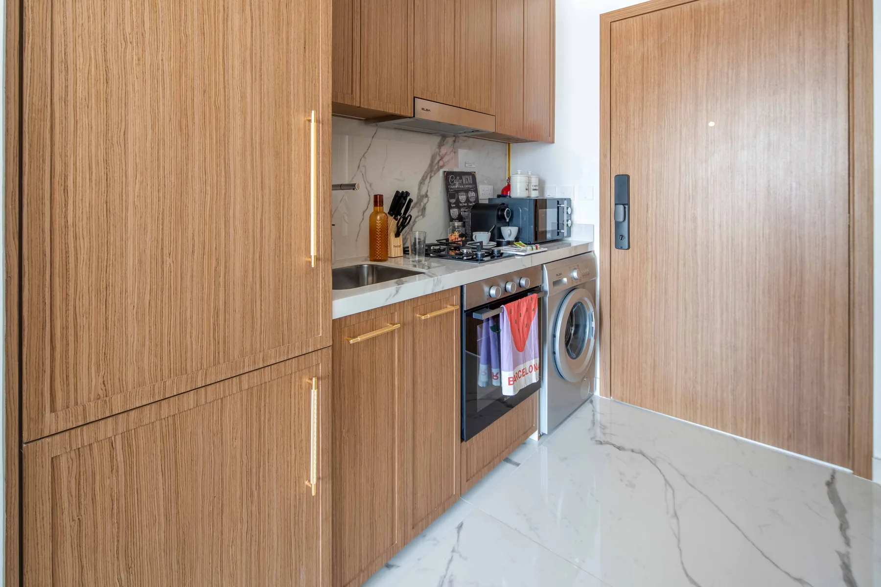 Una cocina compacta con gabinetes de madera, una encimera y electrodomésticos de lavandería.