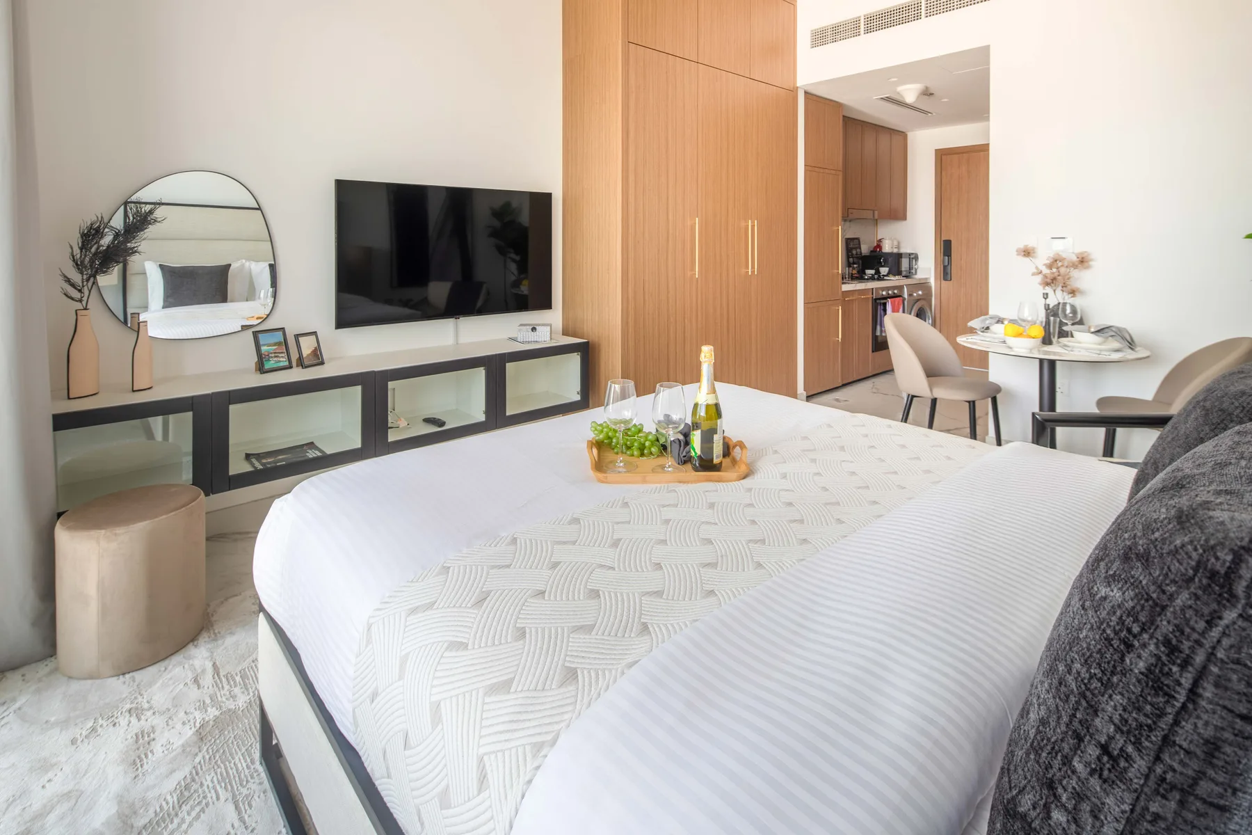 Un dormitorio con una cama bien tendida, un televisor en la pared y una mesa de comedor.