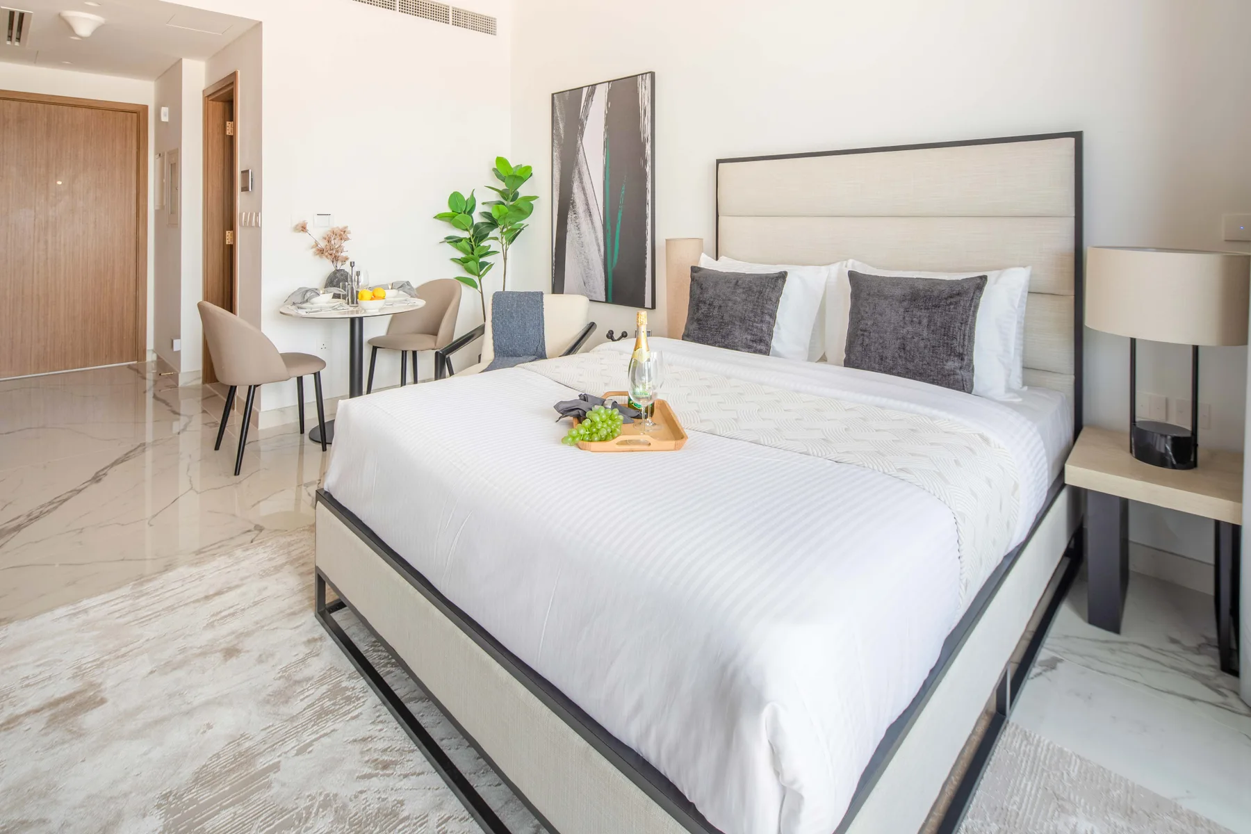 Un dormitorio luminoso con una cama bien hecha y una pequeña mesa de comedor.
