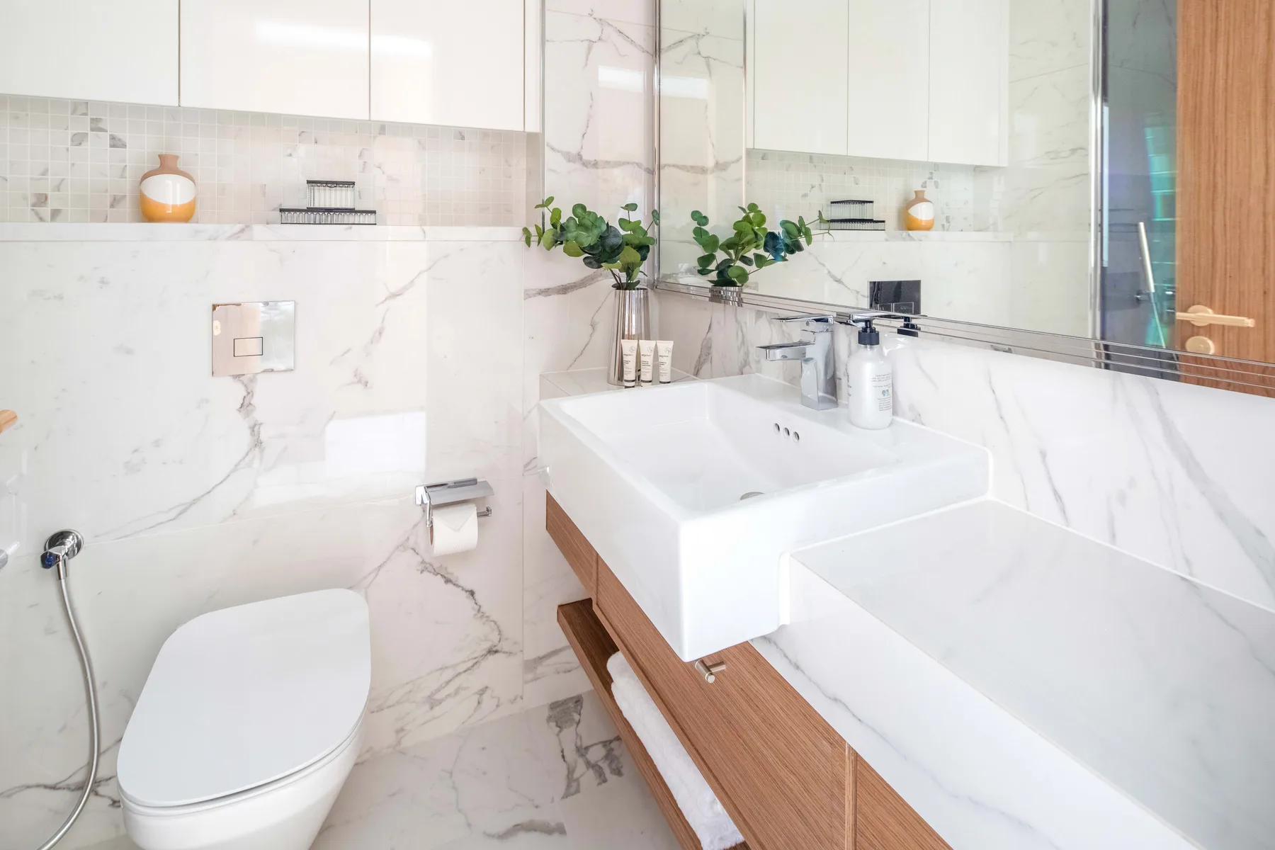 Un baño luminoso con inodoro, lavabo doble y un espejo grande.