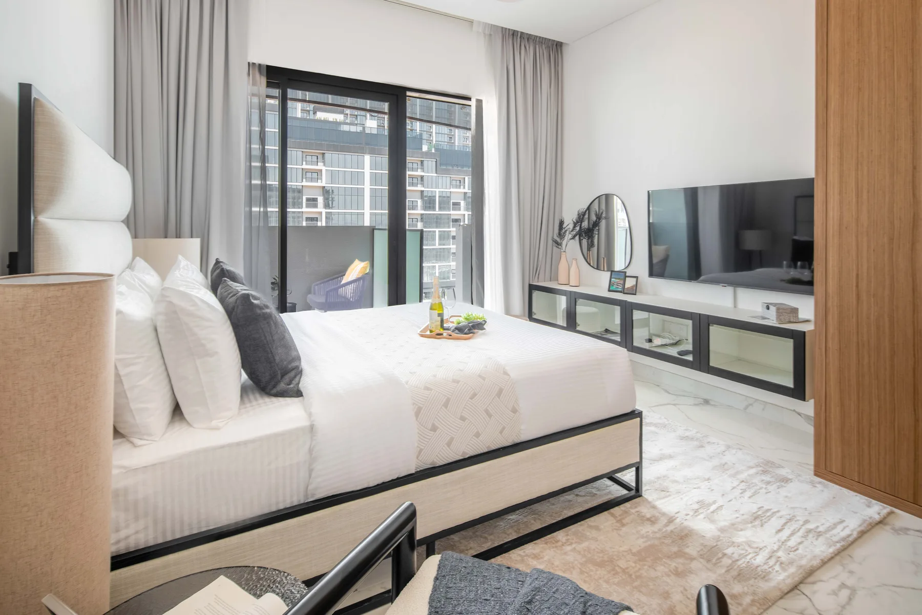 Un dormitorio luminoso con una cama, una ventana amplia y un televisor.